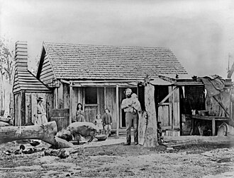 Black and white photo of family and old farmhouse