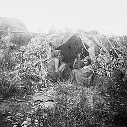 Four Aboriginal people at the entrance to their dwelling, Western Australia, Gustav Riemer ca. 1876
